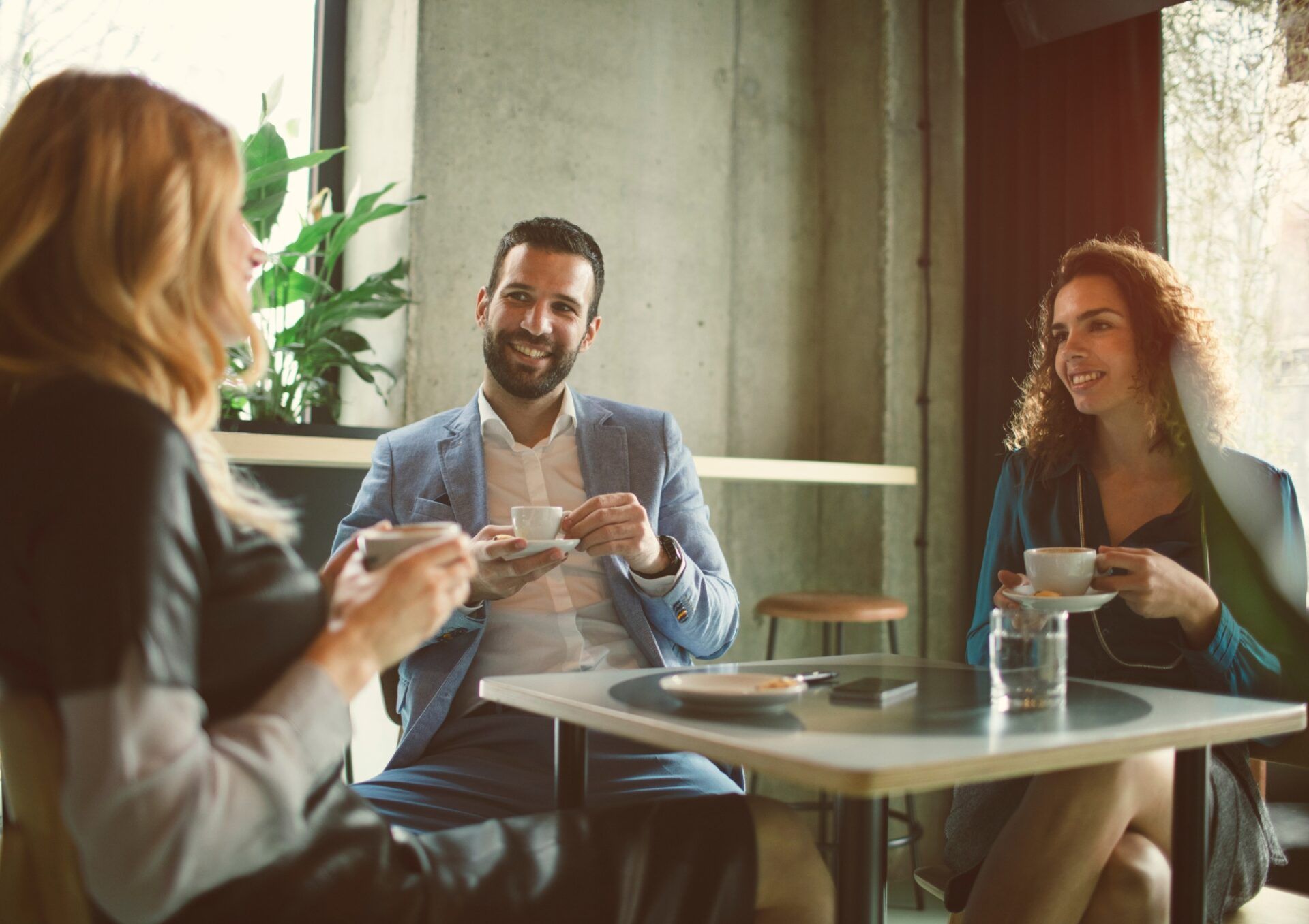 Bild på tre personer som sitter och dricker kaffe runt ett cafébord