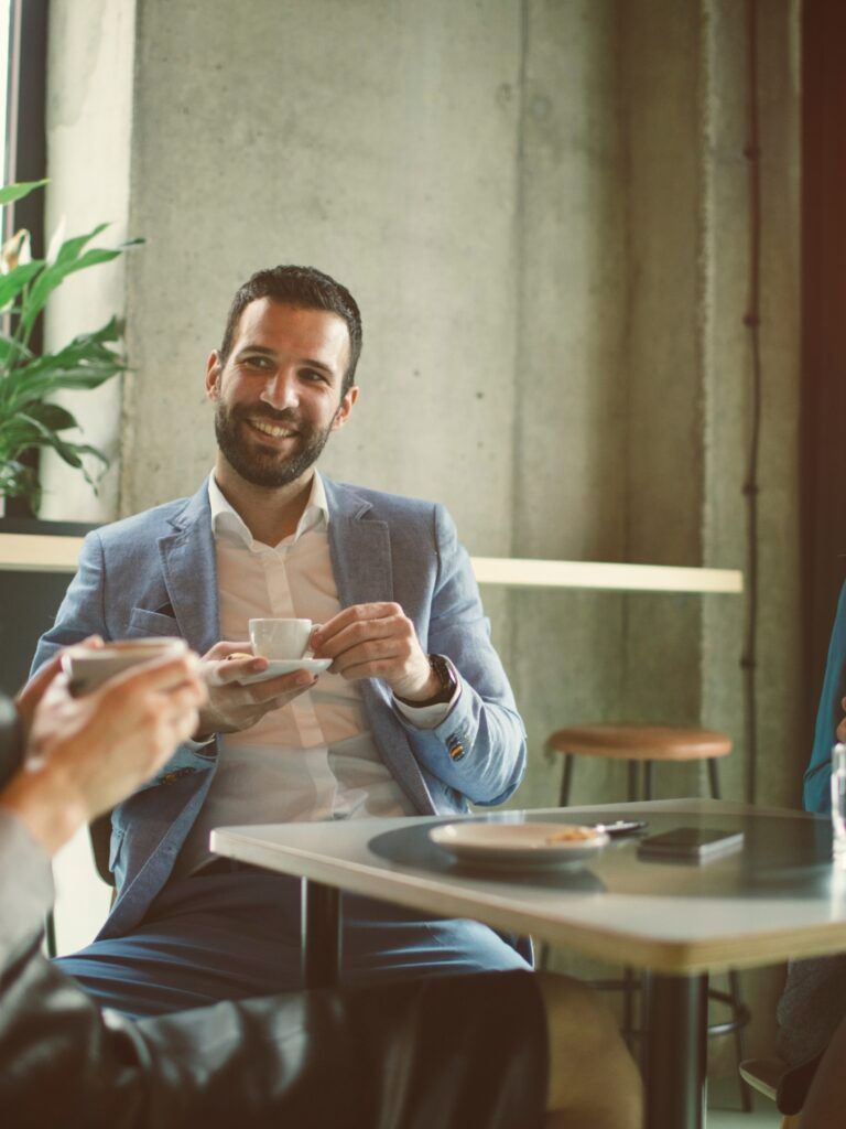 Bild på tre personer som sitter och dricker kaffe runt ett cafébord