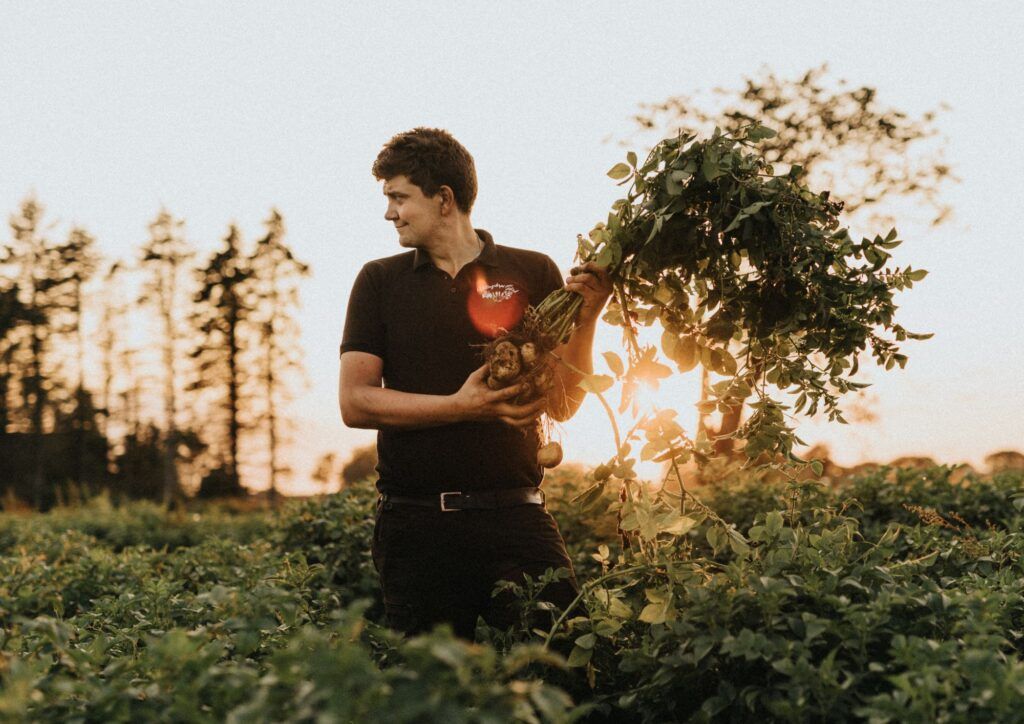 En mörkhårig man står ute i ett potatisfält.