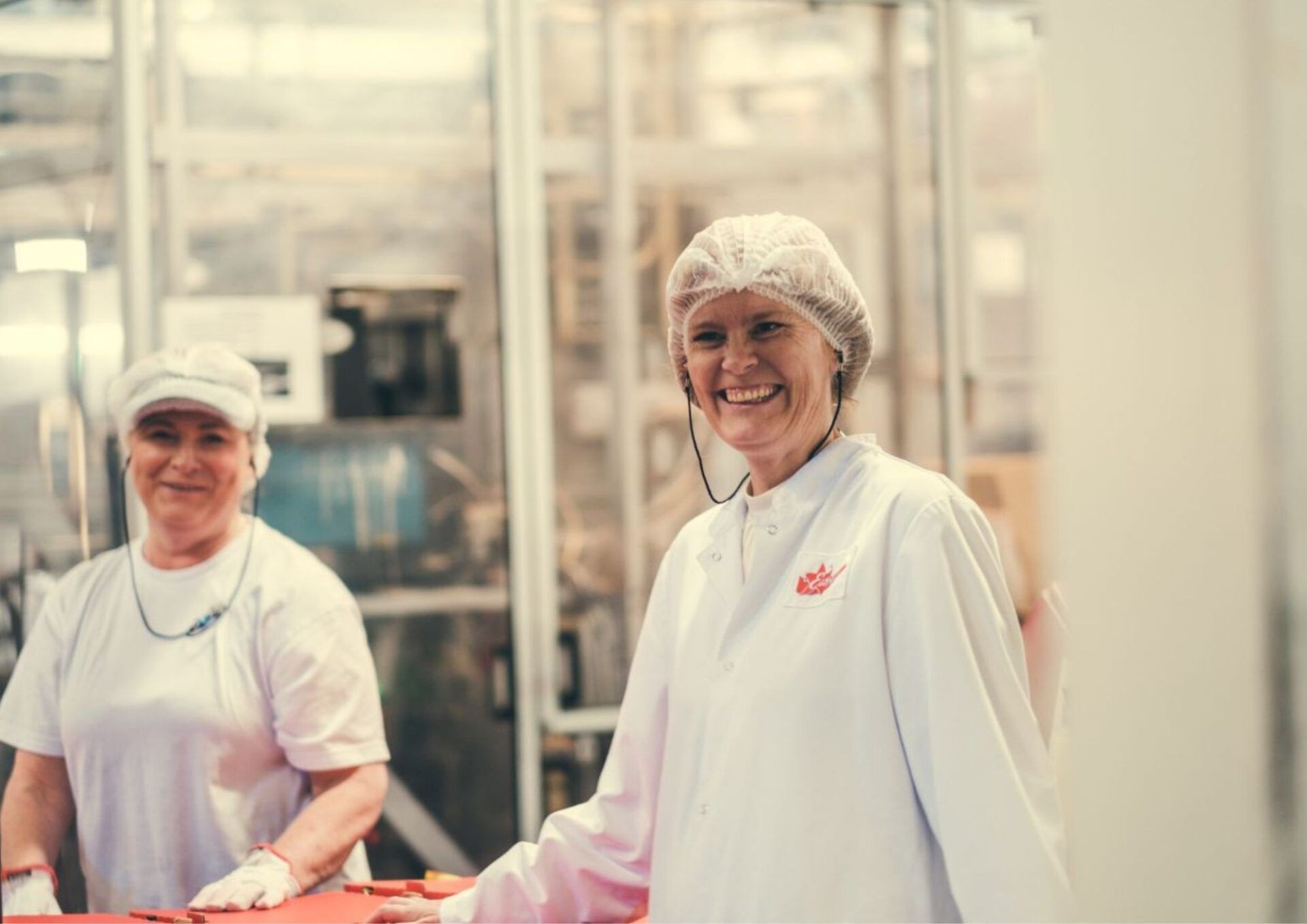 Två kvinnor från Estrella-fabriken skrattar mot kameran. 