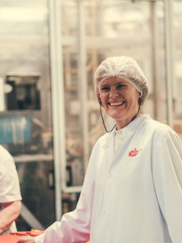 Två kvinnor från Estrella-fabriken skrattar mot kameran. 