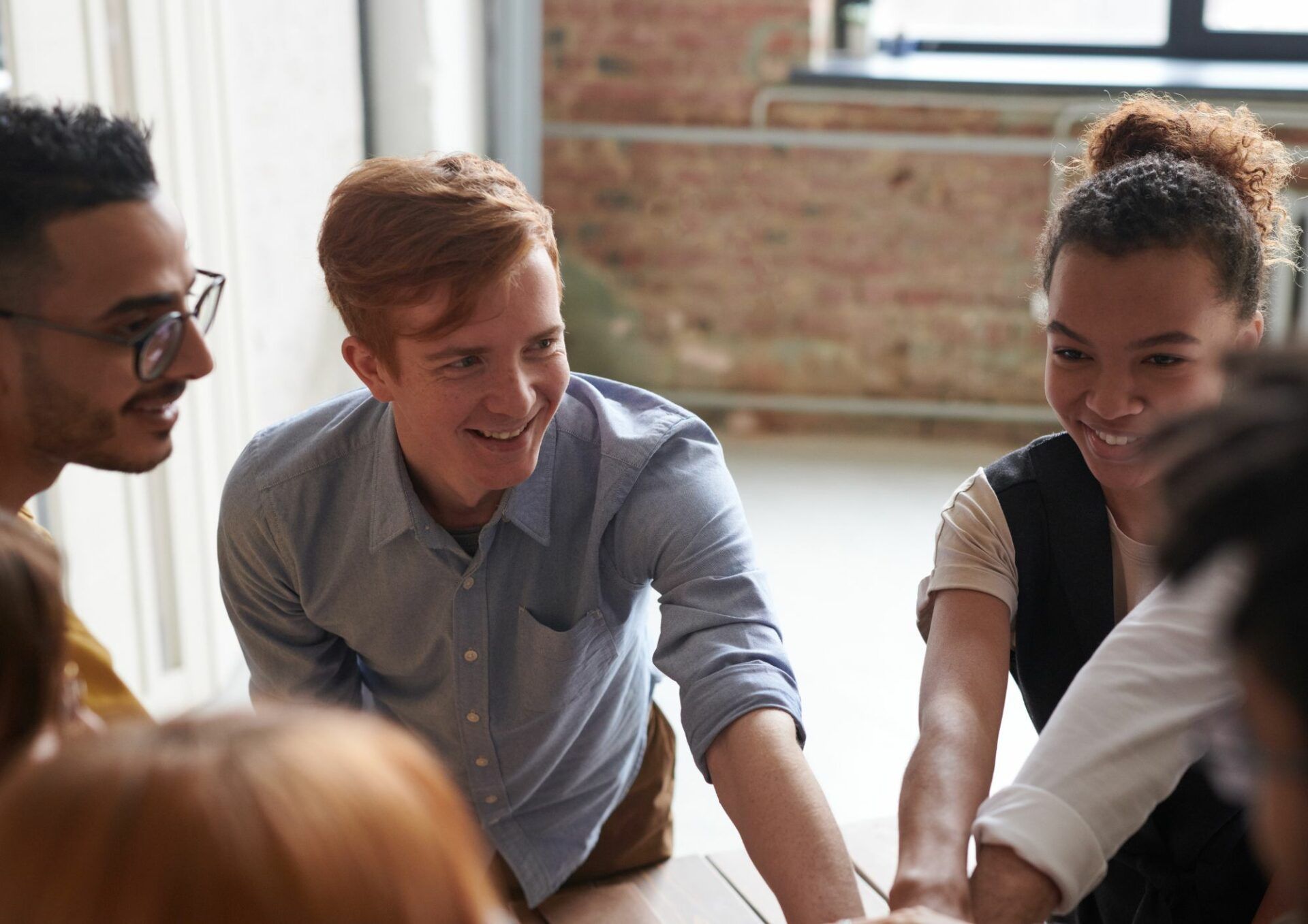 Grupp av personer som har ett möte. En man i blå skjorta i fokus.
