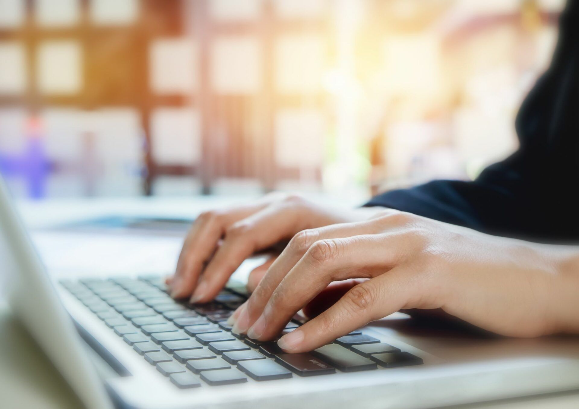 Ett par händer vilar mot tangentbordet på en bärbar dator.