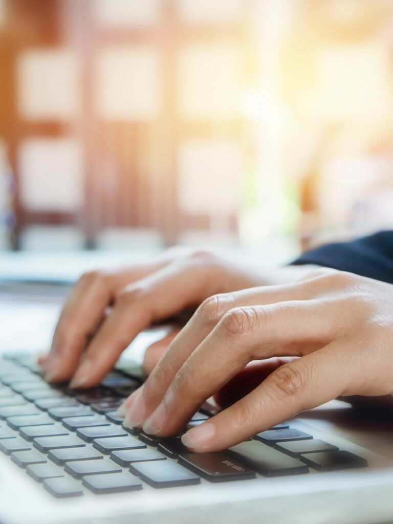 Ett par händer vilar mot tangentbordet på en bärbar dator.