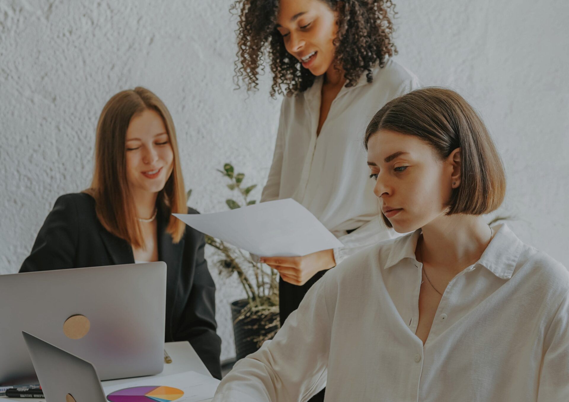 Tre kvinnor jobbar tillsammans i kontorsmiljö