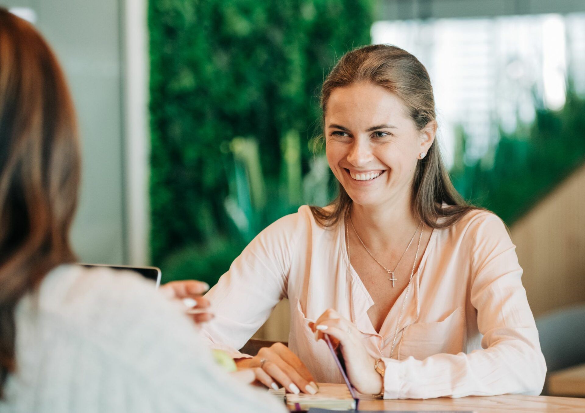 Två kvinnor sitter mittemot varandra vid ett bord i kontorsmiljö.