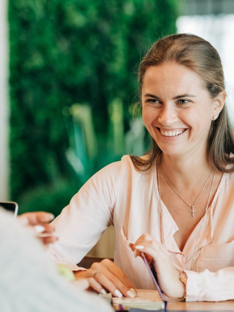 Två kvinnor sitter mittemot varandra vid ett bord i kontorsmiljö.
