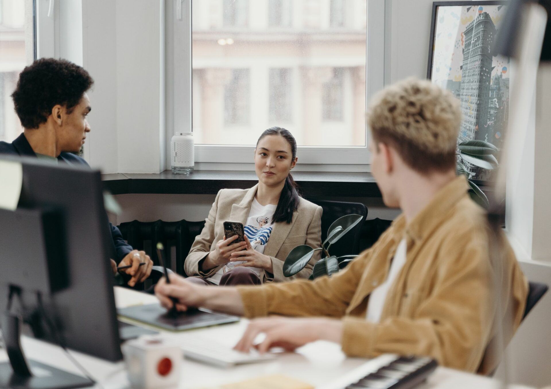 En kvinna och två män sitter i ett öppet kontorslandskap.