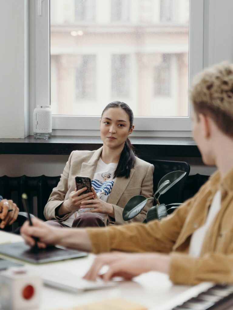 En kvinna och två män sitter i ett öppet kontorslandskap.