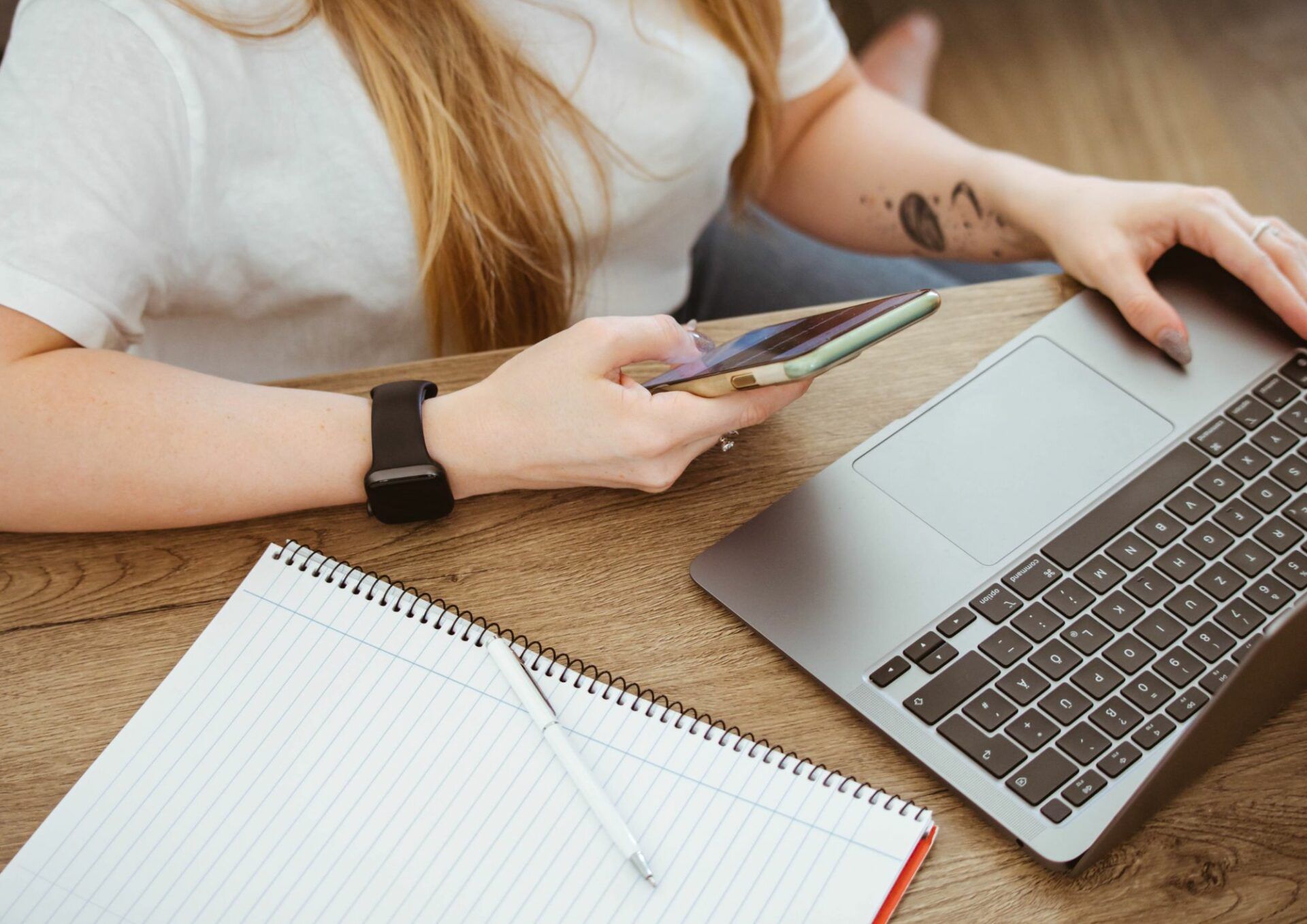 En kvinna arbetar med sin dator och laptop