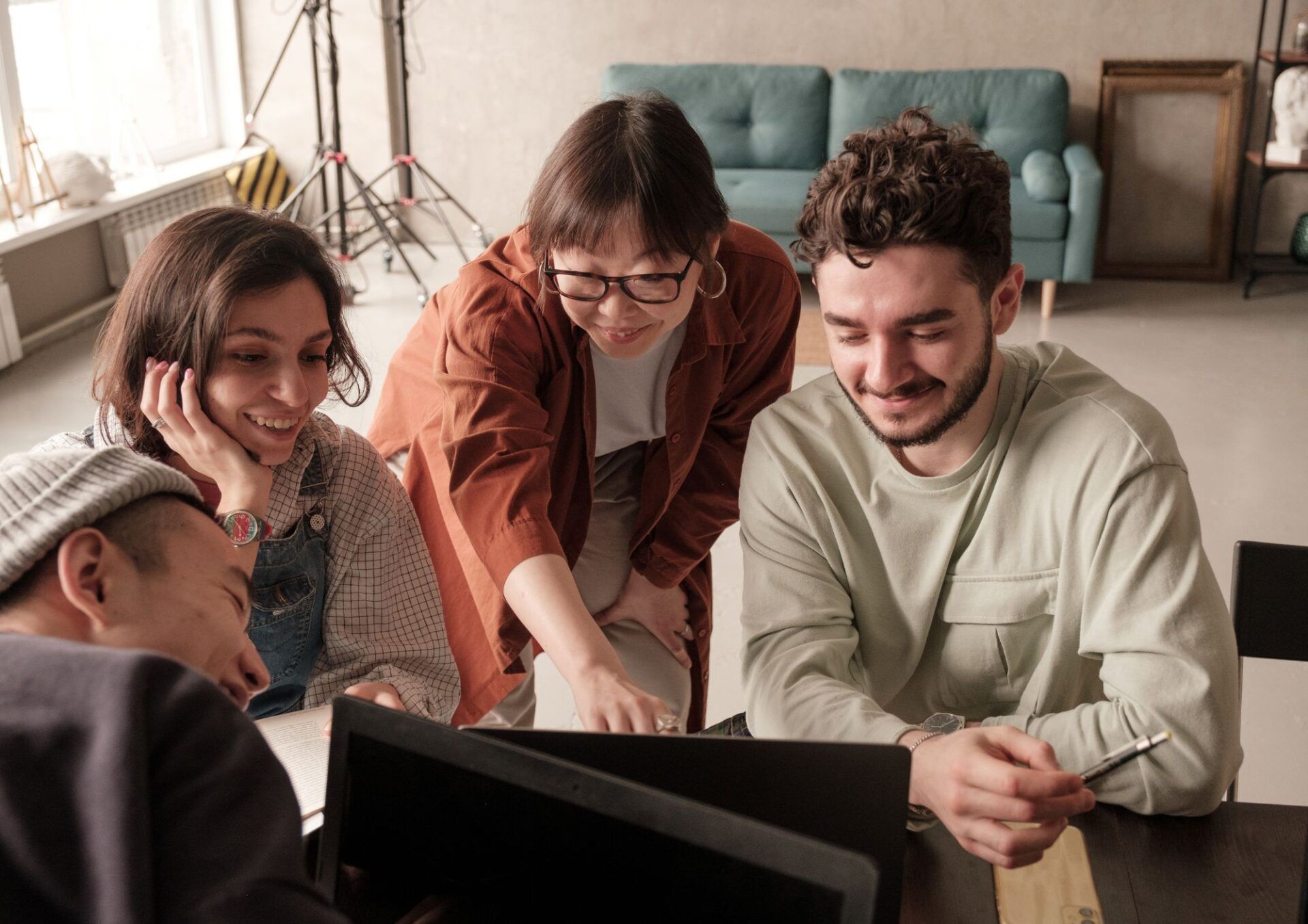 Fyra glada medarbetare samarbetar kring en laptop. 