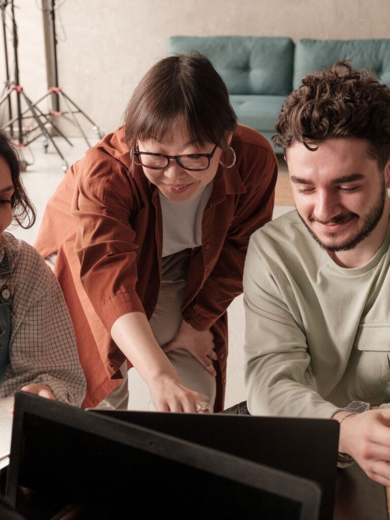 Fyra glada medarbetare samarbetar kring en laptop. 