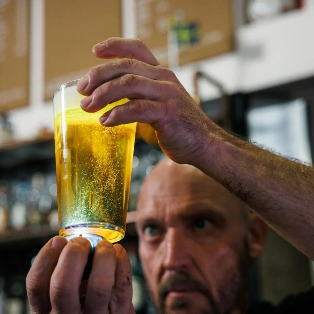 Person som håller upp en glas med bubblande öl