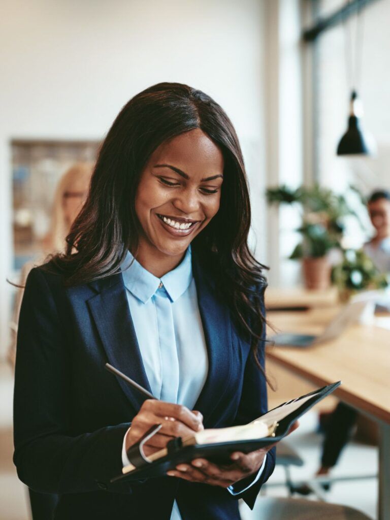 Kvinna ler och skriver i en bok