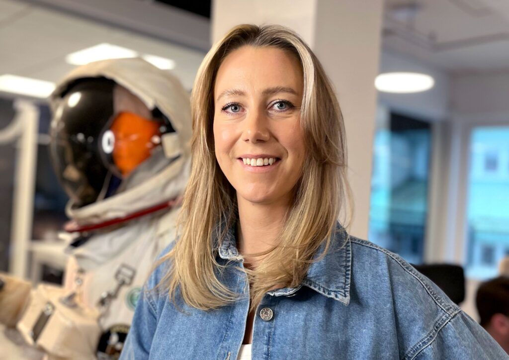 Foto på Emma Häregård. I bakgrunden ser man en rymddräkt.