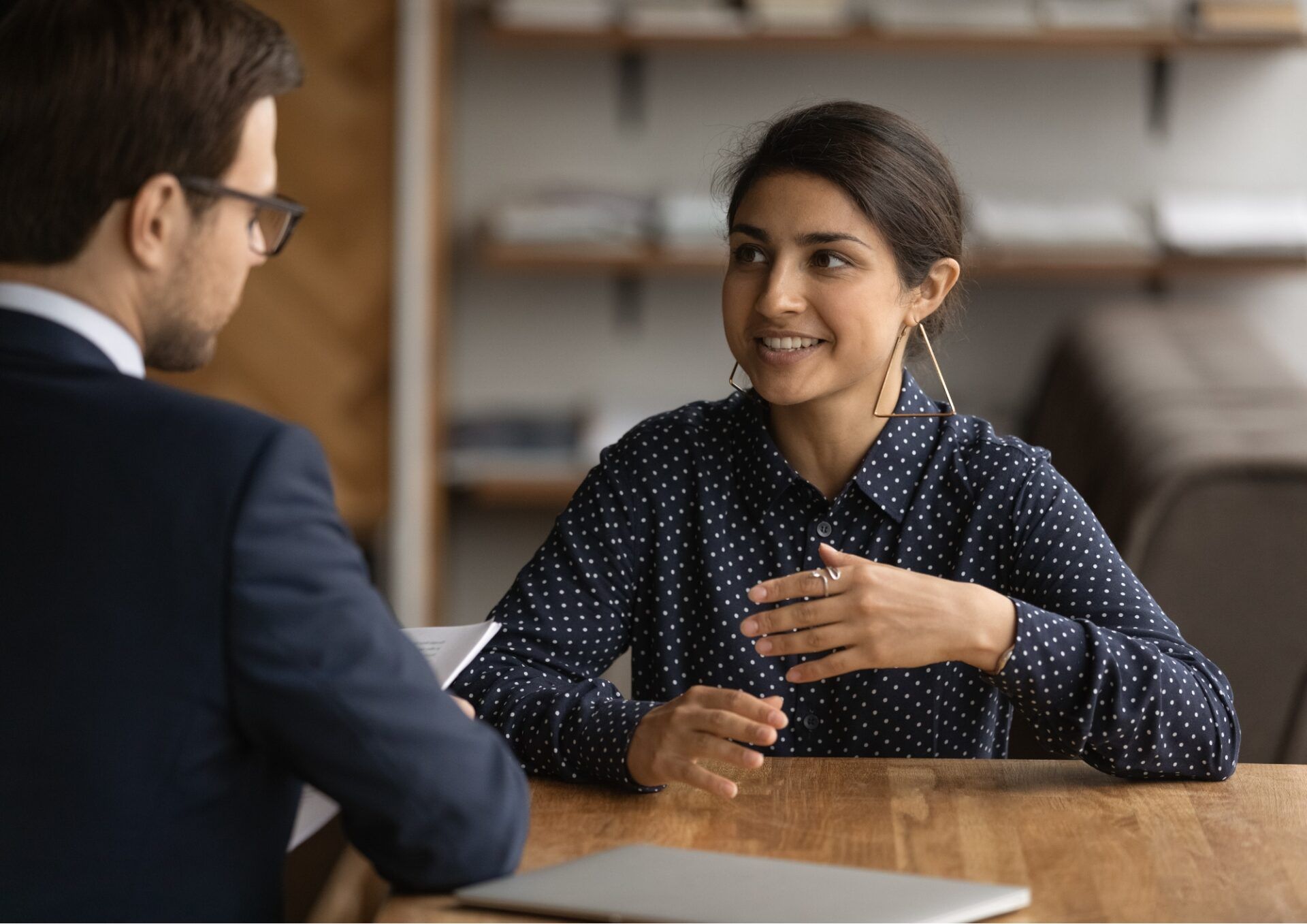 En kvinna och en man sitter ner vid ett bord och pratar med varandra.