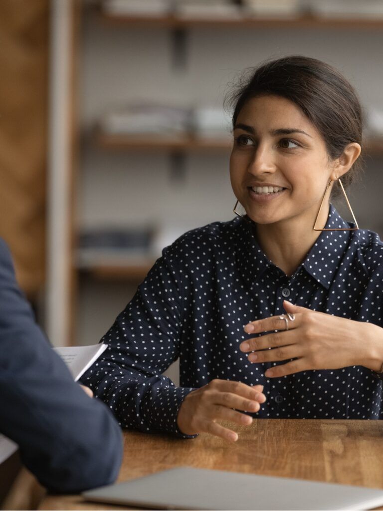 En kvinna och en man sitter ner vid ett bord och pratar med varandra.