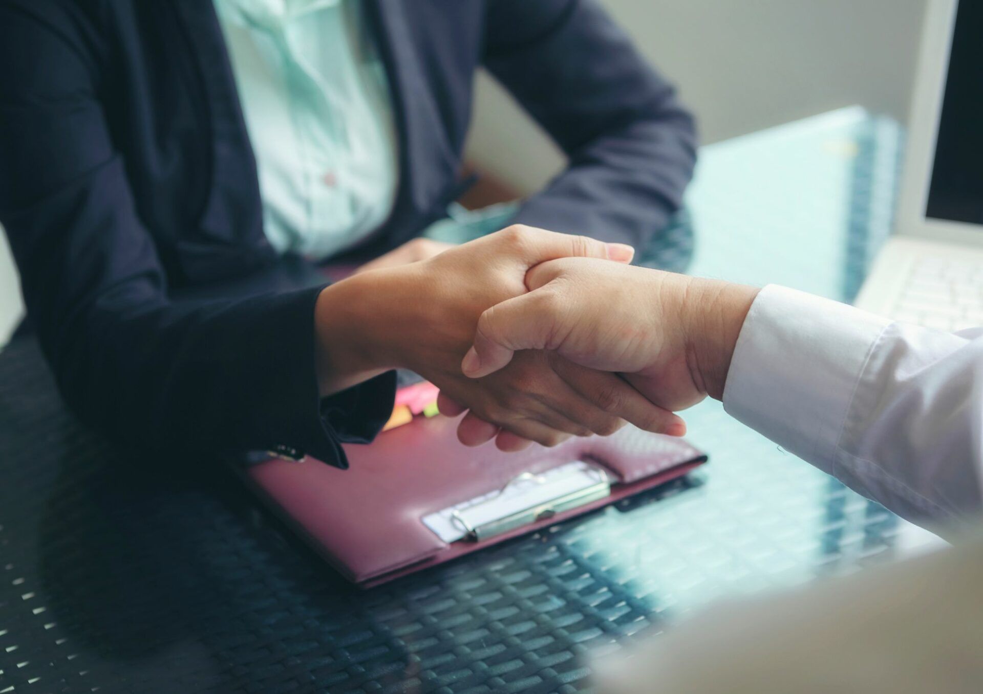 Två människor sitter ner vid ett bord och tar i hand.