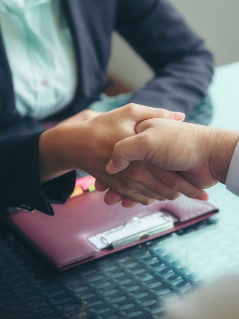 Två människor sitter ner vid ett bord och tar i hand.