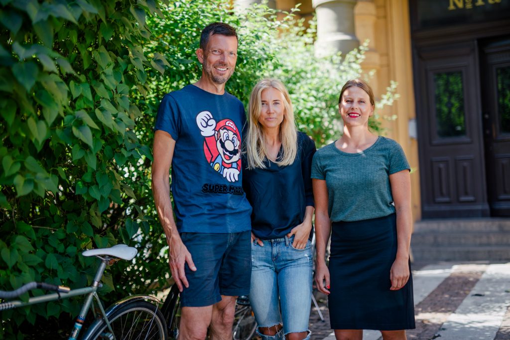 Gruppbild på tre medarbetare på Wint. Fotot är taget utomhus en solig dag.